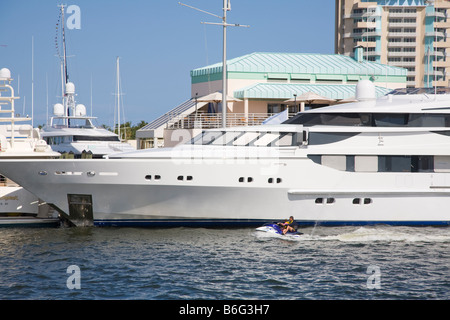 Uomo e bambino equitazione Jet Ski accanto a yacht di lusso sulla Atlantic Intracoastal Waterway a Fort Lauderdale Florida Foto Stock