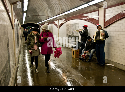 La gente camminare passato buskers in un panno umido e un sottopassaggio. Foto Stock