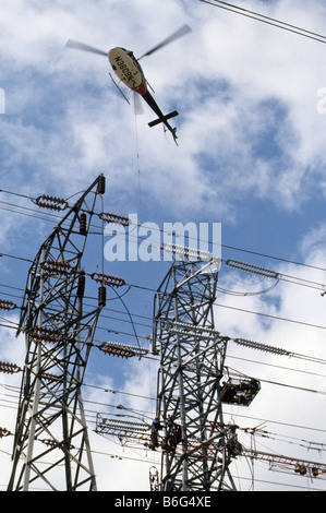 Elicottero serve come gru di antenna per fornire parti di costruzione della linea di alimentazione le torri. Foto Stock