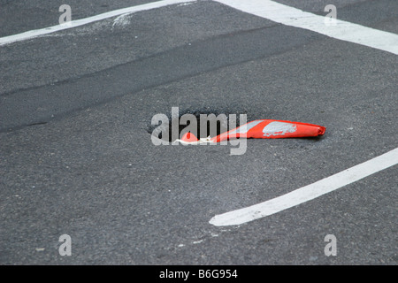 Una spianatura di cono stradale in un foro nella strada. New York Foto Stock