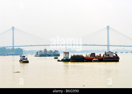 Le barche sul Fiume Hooghly, Calcutta, India, con il Vidyasagar Setu ponte nella distanza. Foto Stock