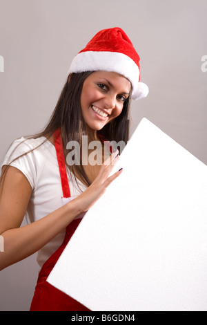 Giovane donna indossa Santa Claus costume tenendo un messaggio bianco bordo Foto Stock