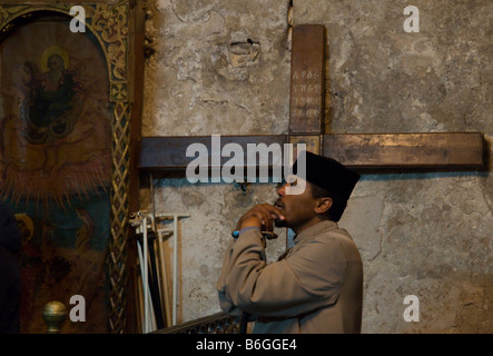 Israele Gerusalemme la città vecchia chiesa del Santo Sepolcro cappella etiope sacerdote etiope pregando con croce di legno in bkgd Foto Stock