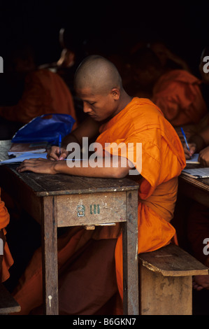 Un giovane monaco buddista di studi presso una scuola monastica - canzone di scuola secondaria superiore, Wat Luang, Paksè, sud Laos Foto Stock
