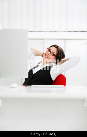 Giovane imprenditrice rilassante in office appoggiata su una sedia Foto Stock
