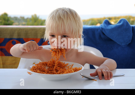 Un ragazzo giovane mangiare pasta mentre sono in vacanza in Italia. Foto Stock