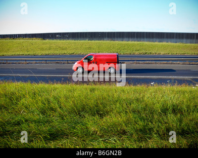 Un rosso consegna van viaggia su una strada vuota Foto Stock