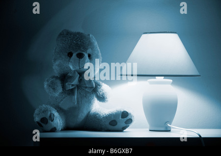 Orsacchiotto di peluche seduta dalla lampada accesa Foto Stock