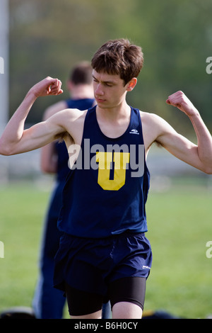 Ragazzo adolescente flettendo i suoi muscoli ad una high school Track & Field soddisfare Foto Stock