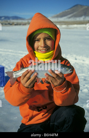 Un ragazzo giovane vestito con una felpa con cappuccio di catture di trote arcobaleno durante la meta inverno attraverso il ghiaccio in Eagle Nest Lago Foto stock Alamy