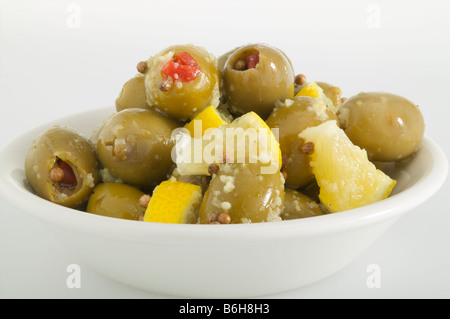 Olive verdi ripiene di pimentos con fette di limone Insalata su sfondo bianco in un piccolo recipiente Foto Stock