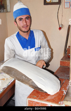 Un baker rendendo tradizionale pane azzimo in un forno tandoori in Turchia Foto Stock