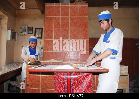 Un baker rendendo tradizionale pane azzimo in un forno tandoori in Turchia Foto Stock