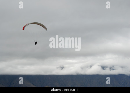 Parapendio sopra Queenstown come visto dal picco di Bobs. Montagne sullo sfondo sono parzialmente oscurate dal basso il cloud Foto Stock