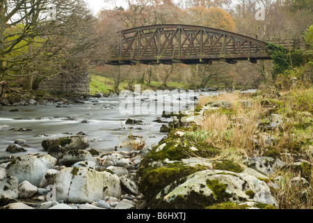 Greta sul fiume che scorre attraverso il legno Brundholme Keswick con uno dei ponti ferroviari da ferroviarie dismesse che attraversano la linea r Foto Stock