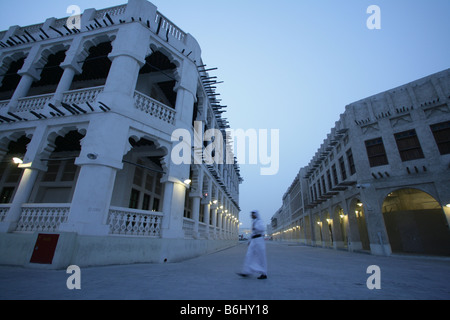 Uomo che cammina passato imbiancare tradizionali edifici al Souq Waqif market con "sporgenti" handal travi al crepuscolo, Doha, Qatar, Medio Oriente Foto Stock