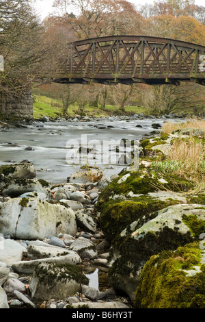 Greta sul fiume che scorre attraverso il legno Brundholme, Keswick, con uno dei ponti ferroviari da disuso linea ferroviaria spanning il Foto Stock