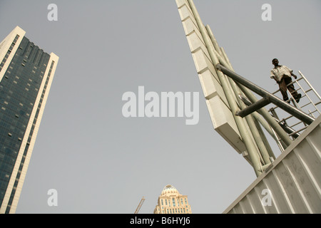 Lavoratore migrante con fiducia di bilanciamento su un tetto di billboard, Doha, Qatar Foto Stock