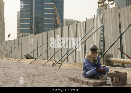 Lavoratore migrante la posa dei mattoni per pavimentazione a Doha, in Qatar. Foto Stock