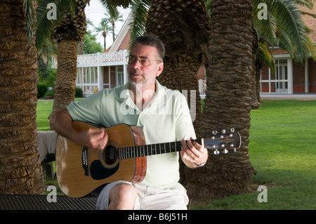 Uomo di mezza età gode di suonare la chitarra nel parco Foto Stock
