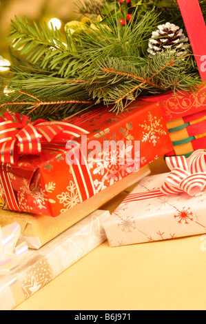Vacanze di Natale in scena con avvolto doni e verdi decorativi nella parte anteriore del albero di Natale illuminato. Foto Stock