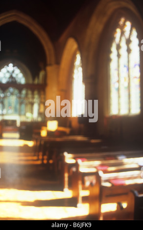 Impressionistica interno di inizio inglese chiesa in stile gotico con una luce calda inondazioni su banchi la navata e il presbiterio Foto Stock