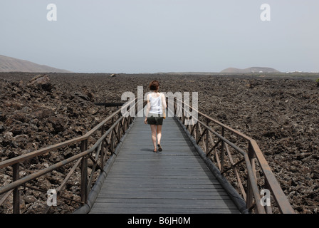 Un turista passeggiate su campi di lava presso il centro visitatori del Parco naturale de los volcanes e Parque Nacional de Tim Foto Stock