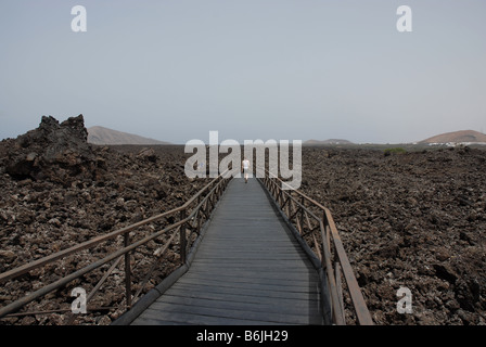 Un turista passeggiate su campi di lava presso il centro visitatori del Parco naturale de los volcanes e Timanfaya in Lanzarote Foto Stock