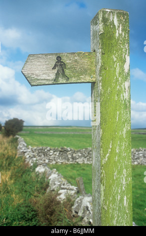 Cartello in legno sul post inciso con immagine iconica del sentiero pubblico walker con stalattite pareti e al di là del campo e di Cumulus nubi Foto Stock