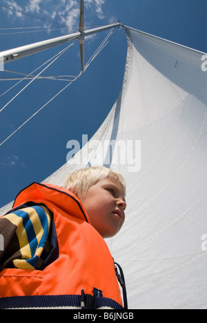 Ragazzo con vela in background di guardare avanti Foto Stock