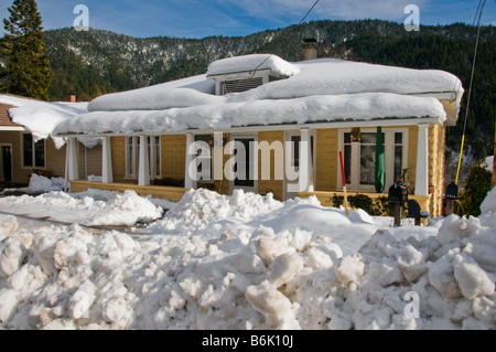 Casa anziani con la neve sul tetto e impilati nella parte anteriore Foto Stock