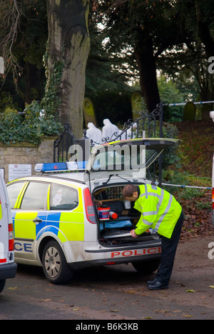 La polizia e gli ufficiali forensi alla ricerca di indizi dopo un crimine è stato commesso in un cimitero del Regno Unito Foto Stock