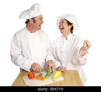 Due chef goofing intorno e ridere in cucina come lavorano isolati su bianco Foto Stock