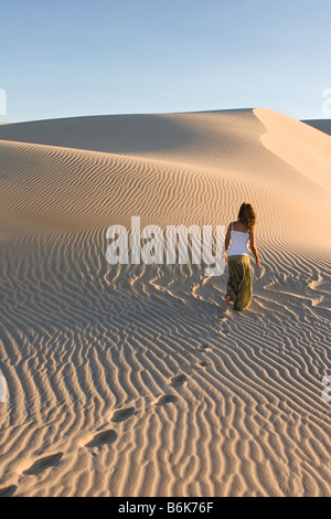 Donna climbing duna di sabbia, Cumbuco, Brasil. Foto Stock