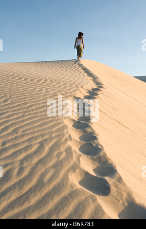 Donna climbing duna di sabbia, Cumbuco, Brasil. Foto Stock