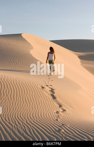 Donna climbing duna di sabbia, Cumbuco, Brasil. Foto Stock