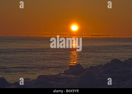 La caccia alla balena Inupiaq equipaggio attende e orologi per passare bowhead balene a bordo di un filo aperto tra i ghiacci durante il tramonto Foto Stock