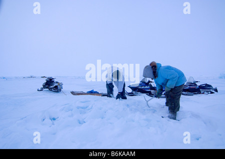 Inupiaq sussistenza whalers rompere il ghiaccio del ghiacciaio con assi di prelevamento per fondere per acqua potabile durante la primavera stagione di caccia alle balene mare Chukchi Foto Stock