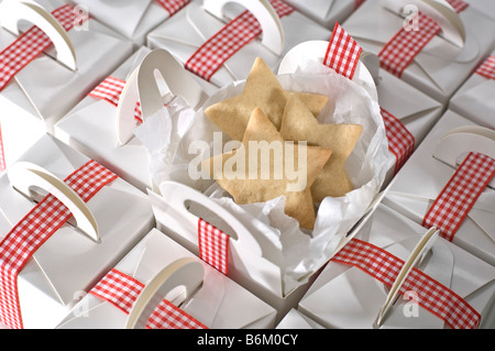 A forma di stella ritagliare dei biscotti confezionati in pianura semplici caselle bianche per regali a Natale. Legato con il rosso Gingham ribbon Foto Stock