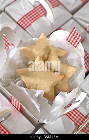 A forma di stella ritagliare dei biscotti confezionati in pianura semplici caselle bianche per regali a Natale. Legato con il rosso Gingham ribbon Foto Stock