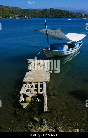 Una piccola barca ancorata ad un molo di legno nelle calme acque blu sulla Costa turchese, Fethiye, Turchia Foto Stock