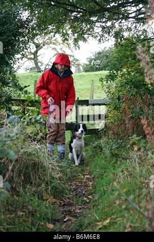 Una donna passeggiate con il cane sotto la pioggia Foto Stock