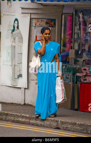 Donna in piedi sulla strada di Little India di Singapore in attesa per autobus Foto Stock