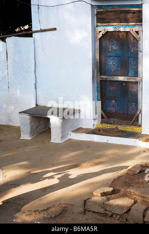 Villaggio indiano home e portale con ombra di bambini a giocare una mano di gioco battendo sul terreno. Andhra Pradesh, India Foto Stock