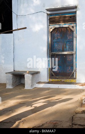 Villaggio indiano home e portale con ombra di bambini a giocare una mano di gioco battendo sul terreno. Andhra Pradesh, India Foto Stock