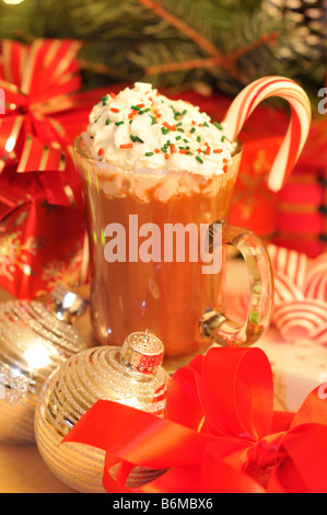 Bicchiere di 'cioccolata calda con panna montata" spruzza e candy cane a Natale sul tavolo. Foto Stock