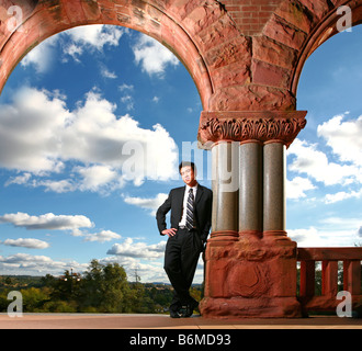 Felice giovane imprenditore asiatici o studente in cima a scale di un grande edificio Foto Stock
