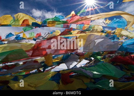 Bandiere di preghiera sbattimenti nel sole di mezzogiorno sulla cima di un affioramento al lago Namtso, Tibet Foto Stock