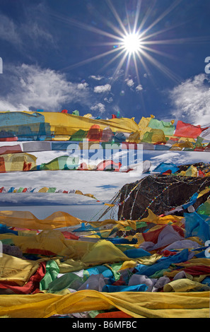 Bandiere di preghiera sbattimenti nel sole di mezzogiorno sulla cima di un affioramento al lago Namtso, Tibet Foto Stock