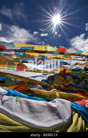 Bandiere di preghiera sbattimenti nel sole di mezzogiorno sulla cima di un affioramento al lago Namtso, Tibet Foto Stock